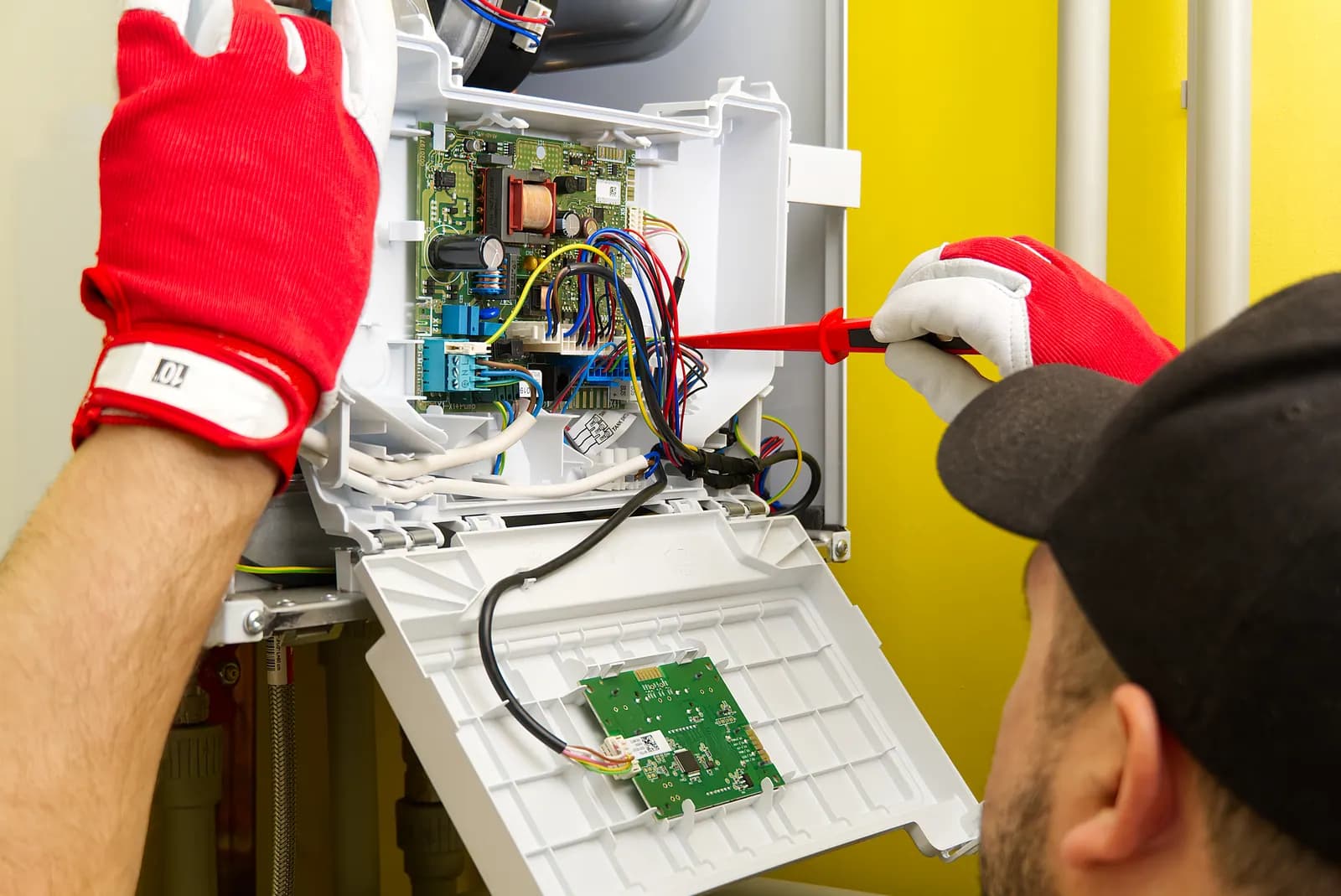 Teknisyenin koruyucu ekipmanla elektrik bağlantısı üzerinde çalıştığı görsel